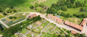 Vue aérienne de l'Arche de la Nature au Mans, un espace naturel verdoyant avec fermes, jardins et étangs, le lieu idéal pour votre balade à vélo au Mans.