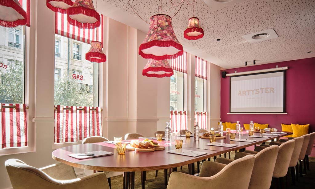 Salle de séminaire La Rotonde, vaste table de réunion préparée pour recevoir les invités du séminaire, écran géant au fond de la salle.