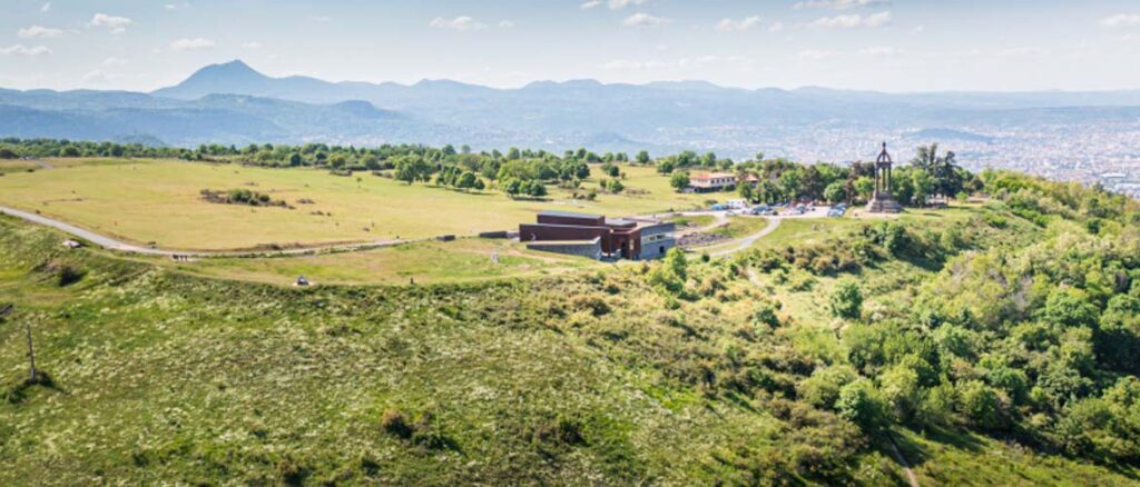 Vue aérienne du Plateau de Gergovie avec son musée, son monument, et les monts d’Auvergne en arrière-plan