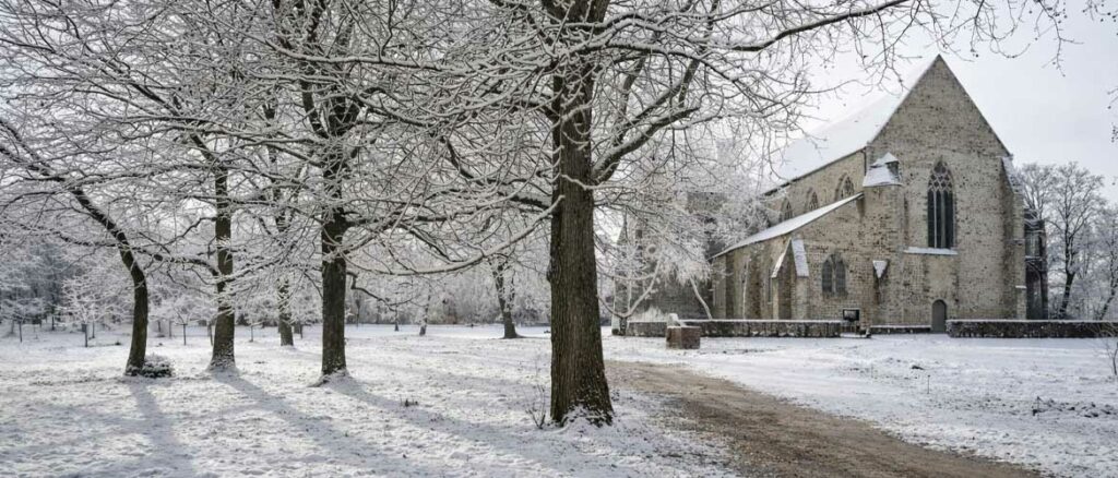 Balade à vélo au Mans en hiver avec une halte à l’abbaye de l’Épau enneigée, dans un paysage calme et hivernal.