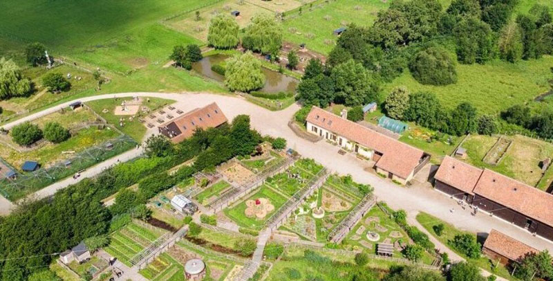 Vue aérienne de l'Arche de la Nature au Mans, un espace naturel verdoyant avec fermes, jardins et étangs, le lieu idéal pour votre balade à vélo au Mans.